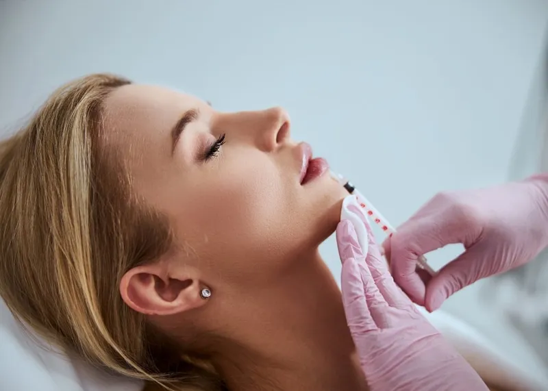 A doctor injects dermal filler into a patient's cheek to restore lost facial volume.