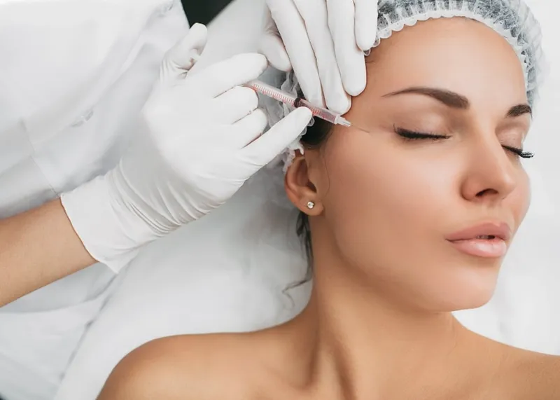 A specialist examines the under-eye area of a patient before a light filling treatment for dark circles.