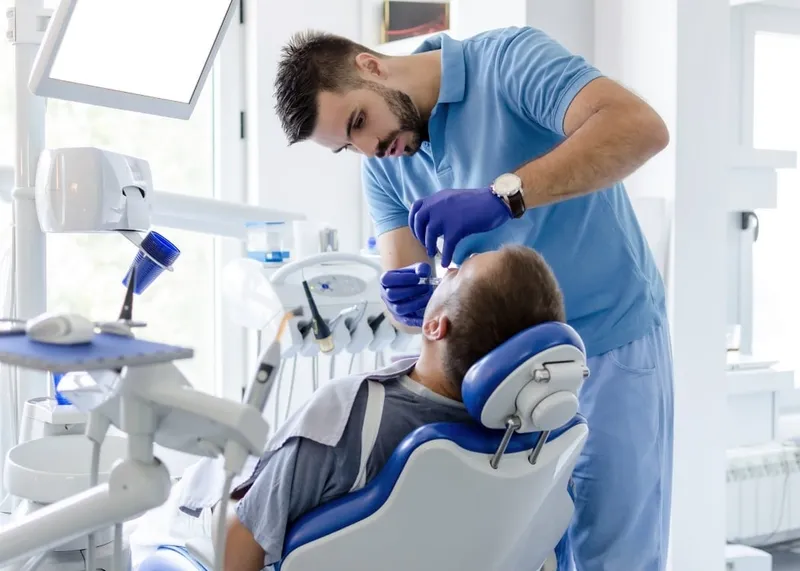 A Turkish dentist reviews a dental X-ray with a patient during a consultation.