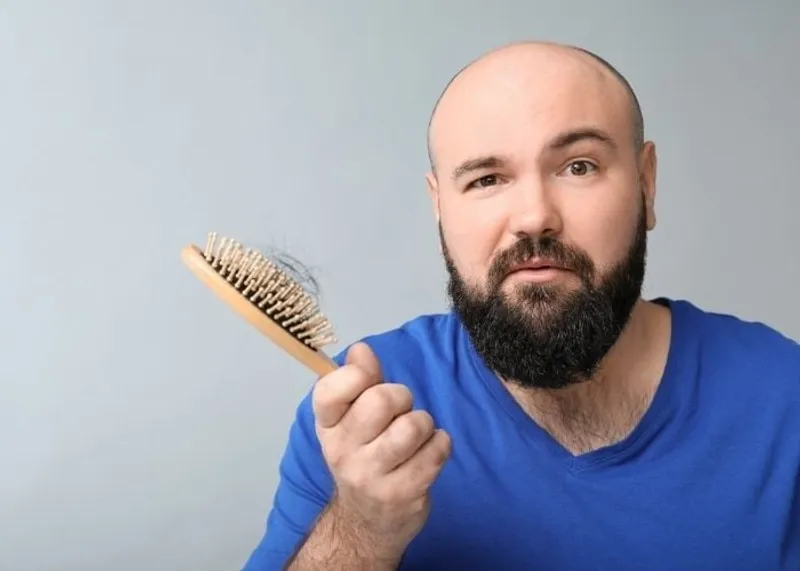 A man checks his receding hairline in the mirror while considering a hair transplant.