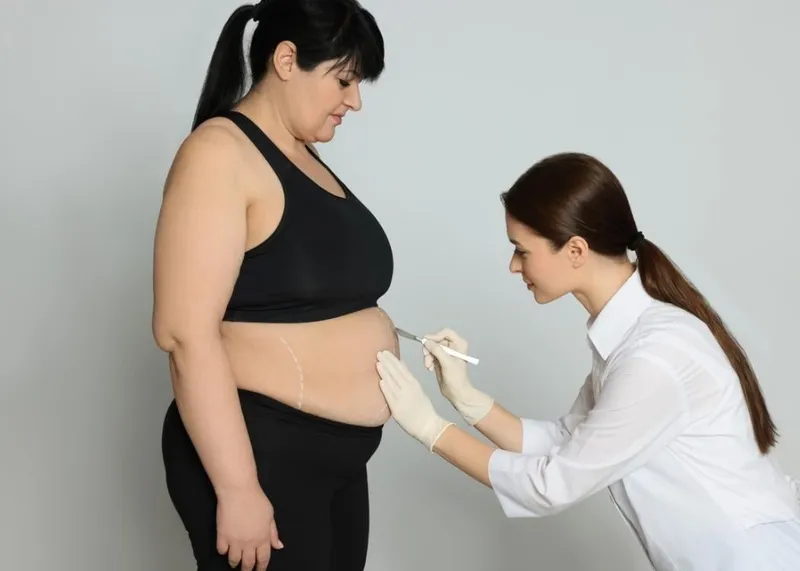 Chirurg berät eine Patientin zu Optionen für Bauchdeckenstraffung und Fettabsaugung bei der Planung eines Mommy Makeovers.